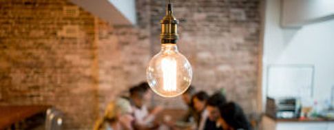 Vintage Glühbirne hängt von der Decke in der Mitte des Bildes mit einem Büro im Hintergrund